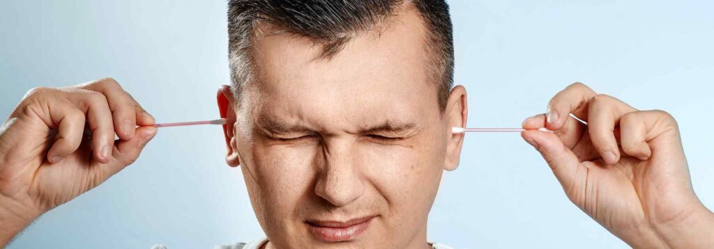 Man hurting his ears with cotton buds